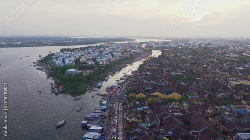 Drone flying along Thu Bon River toward Hoi An Ancient Town at sunset, Vietnam
