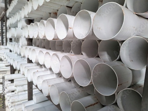 Canvas Print Close up perspective of stacked white PVC pipes on a metal rack in a warehouse