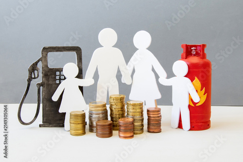 фотографія A family stands between a gas pump and a gas tank, surrounded by stacks of coins