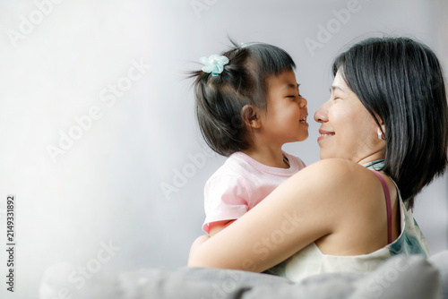 Happy mother holding her smiling toddler in a warm embrace, expressing love, family bonding, care, happiness, trust, and precious moments together at home, Asian Thai people