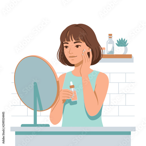 Woman applying facial serum in front of mirror