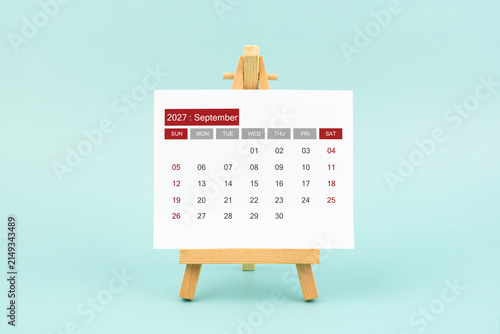 Calendar page for September 2027 with wood easel on a blue background.