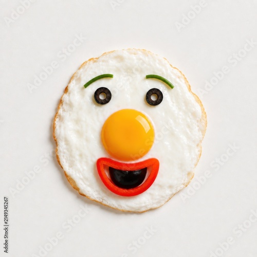 Excited fried egg face made with vegetables on white background