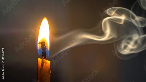 Burning candle flame with elegant flowing smoke trail.