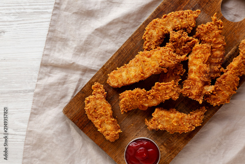 Organic Crispy Chicken Strips with Ketchup on a Wooden Board, top view. Copy space.