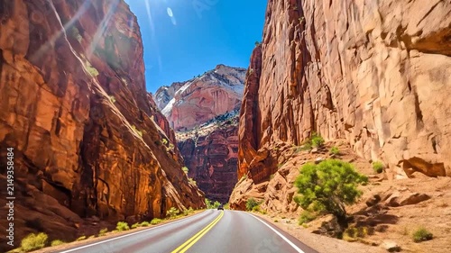 Empty road winding through high red rock canyon.