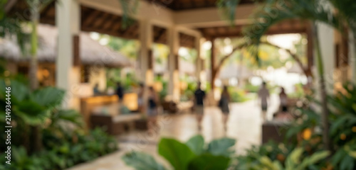 Fully blurred tropical resort hotel lobby with abstract natural architecture, elegant reception forms and soft guest silhouettes. Premium hospitality background for travel and vacation branding