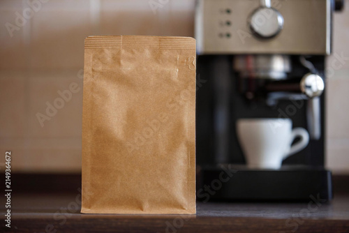 Realistic brown kraft coffee bag mockup displayed in a cozy coffee shop environment. Perfect for coffee branding, packaging design, and product marketing.