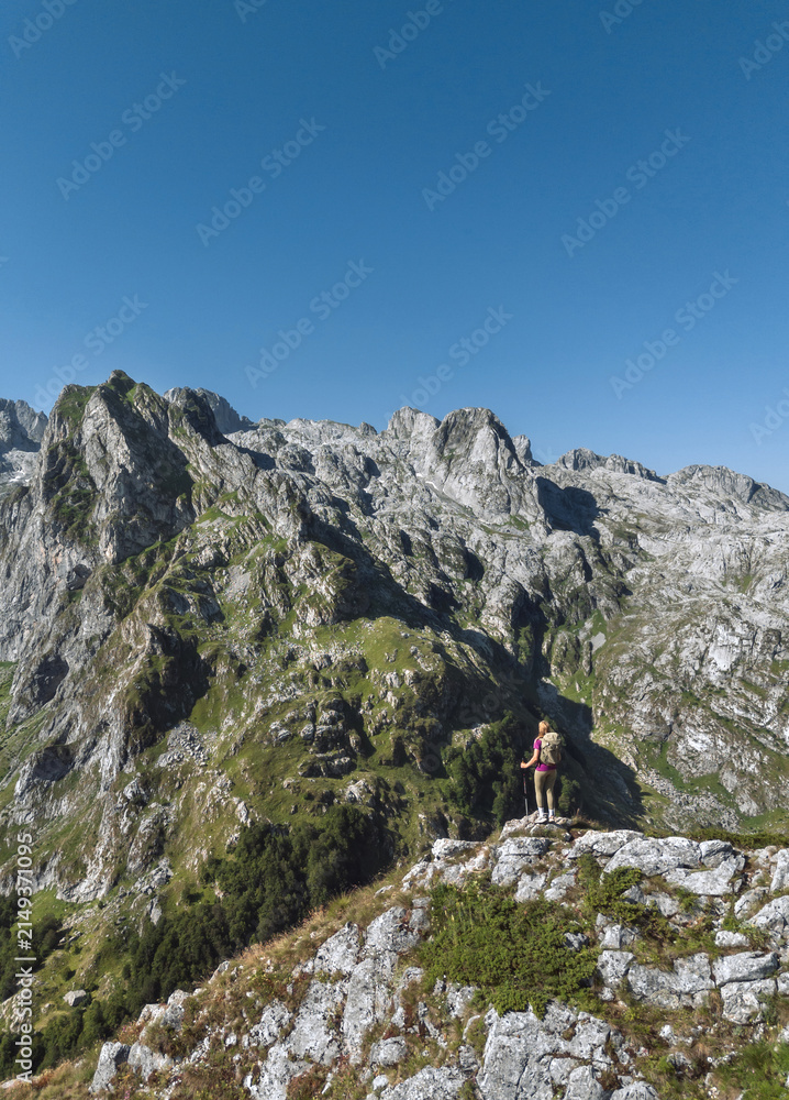 Fototapeta premium Hiker Standing on Rocky Summit Overlooking Valley