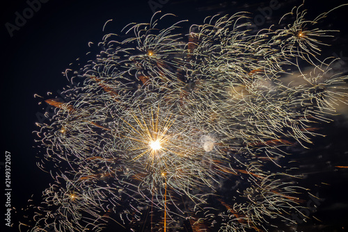 Golden fireworks display with wavy sparkling trails in the night sky