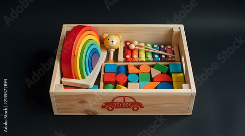 Organized wooden toy storage box containing stackable blocks and musical toys
