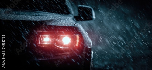 Close-up of a car taillight in heavy rain at night