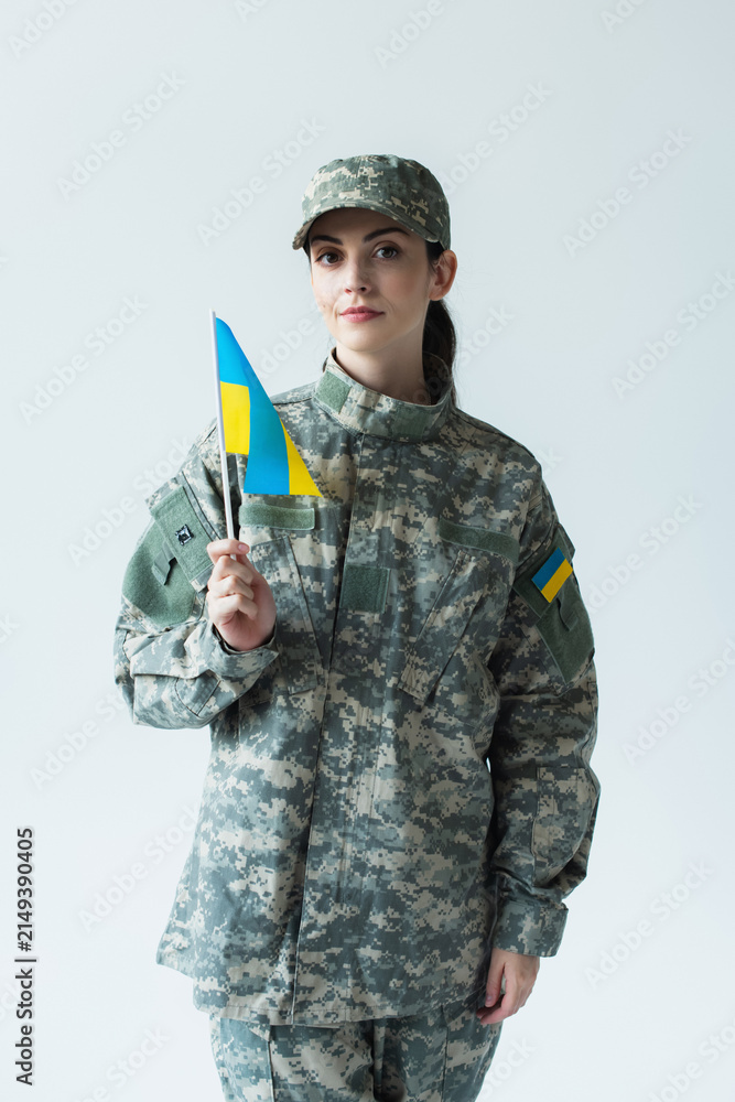 Fototapeta premium Young beautiful woman proudly holding Ukraine flag in military uniform on Independence Day