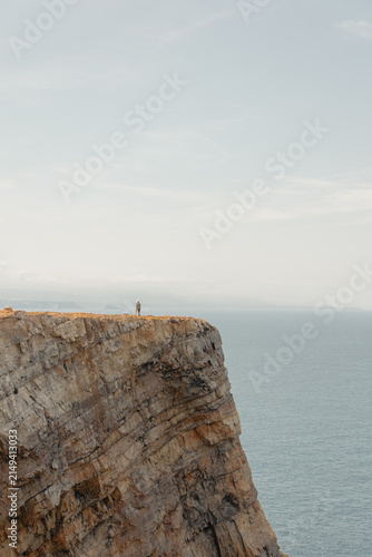 Bild auf Leinwand People standing on a rugged cliff face, experiencing the breathtaking coastal la