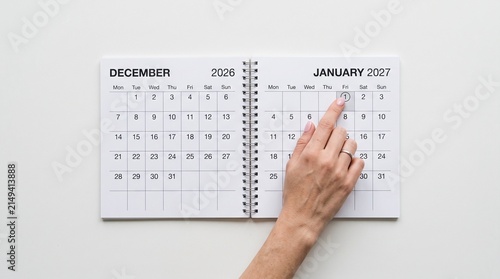 Planning future business goals. Flipping page to 2027 year. Time management and reporting. End of 2026 year project. A  paper desk calendar. The year 2027 begins on the calendar. Happy New Year