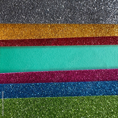 Horizontal strips of multi-colored glitter paper and matte teal cardstock