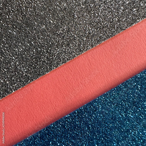 Diagonal layers of silver glitter, matte coral paper, and blue glitter texture
