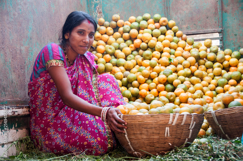 Woman vendor selling oranges at the street, India.