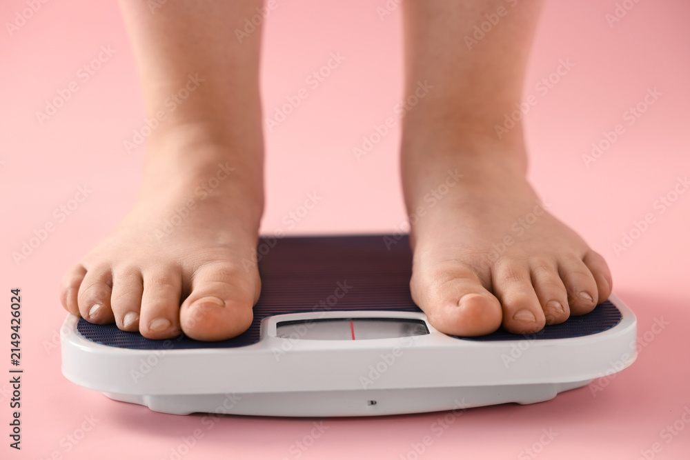 Fototapeta premium Overweight woman on scale against pink background, closeup