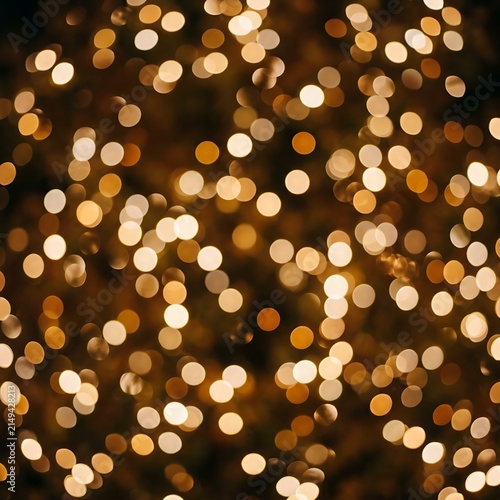 Golden shimmering lights blurred into soft circular bokeh dots providing a magical warm festive party atmosphere backdrop.