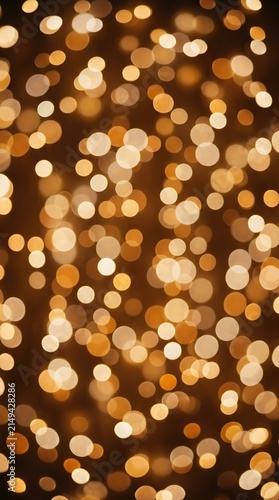Golden shimmering lights blurred into soft circular bokeh dots providing a magical warm festive party atmosphere backdrop. 