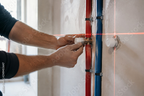 Trabajo de instalación de tuberías en una pared con láser de nivel en una construcción