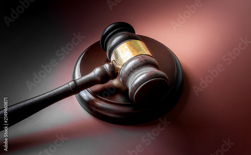 Wooden judge gavel with sound block on dark background with dramatic side lighting, court justice and law concept