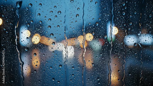 Raindrops on window glass with blurred city night lights background