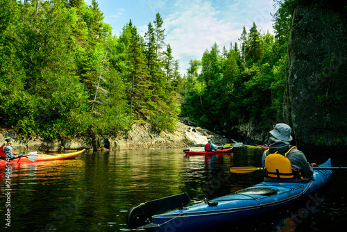 Sea kayakers explore rocky river waterfall channel