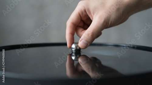 Individual's hand delicately placing a silver on water illustrating business resilience and the fluidity of success