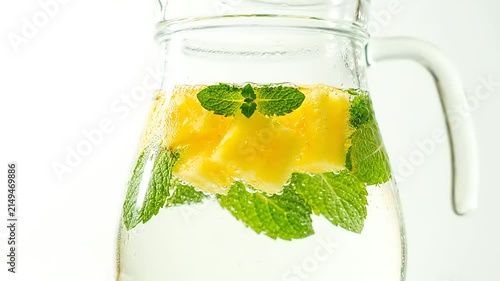 Refreshing infused water in a glass pitcher with fresh pineapple chunks and mint leaves for a healthy summer drink