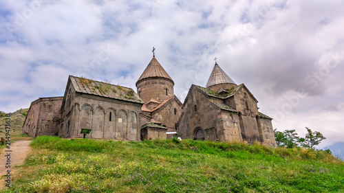 Konstfotografi Historic Armenian Goshavanq Monastery ruins on grassy hillside under cloudy skie