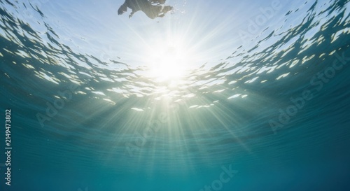 Person diving into sunlit ocean underwater view with light rays