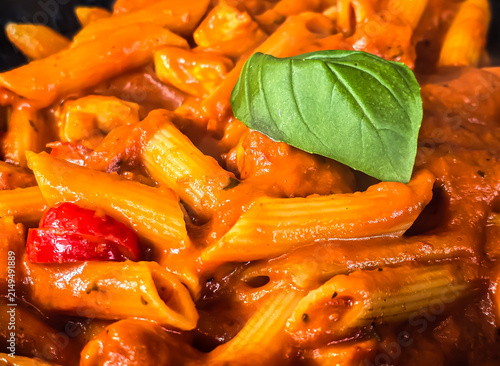 Penne pasta in rich tomato sauce topped with fresh basil