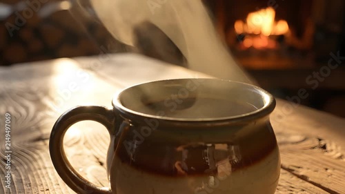 Steaming ceramic mug on wooden table near fireplace.