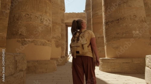 Woman tourist exploring Karnak Temple in Luxor walking between rows of ancient massive columns of Hypostyle Hall, Egypt tourism tour