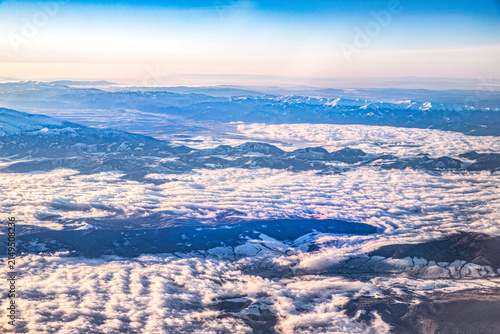 scenic view of snow covered mountains and fluffy clouds from airplane window