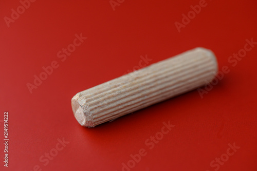 Foto A simple wooden dowel showcases its smooth texture and natural color against a vibrant red background, inviting art enthusiasts and builders alike to envision their next creation