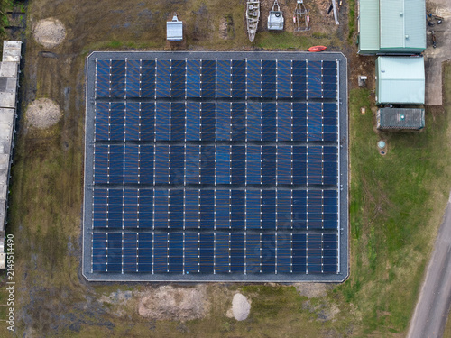 Aerial view of the solar powered waste water treatment plant featuring a grid of dark blue solar panels on a gravel base surrounded by grass in Byron Bay, New South Wales, Australia.