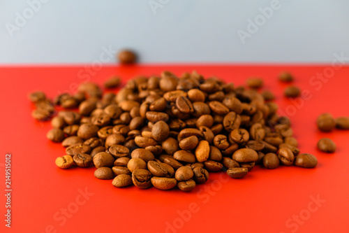 Quadro su tela A mound of rich, brown coffee beans rests on a bright, red surface