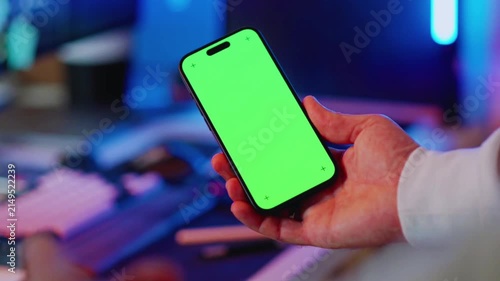 Hand Holding Smartphone with Green Screen in Modern Technology Environment
