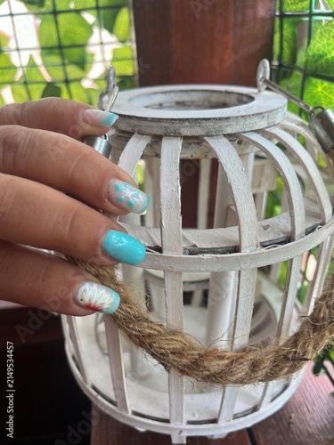 фотографія Mano mostrando manicura decorada con motivos veraniegos sobre un farol de madera