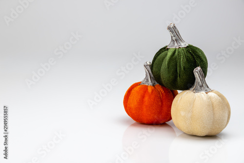 Fotografie Stacked trio of colorful velvet pumpkins on white background.