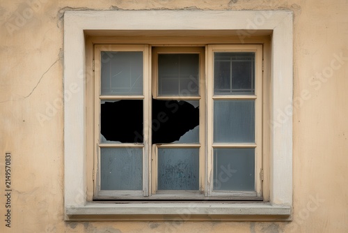 Broken wooden window in weathered wall.