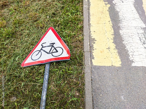 Foto Triangular bicycle warning sign lying on green grass outdoors