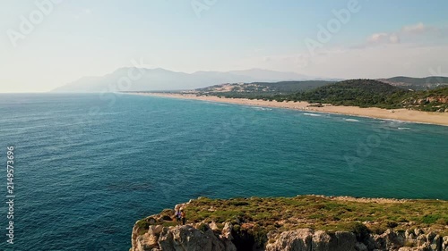 Man exploring rocky hills aerial view near Patara beach in Antalya Turkey. Drone shot capturing an adventurer walking on a rugged cliff overlooking the Mediterranean sea.