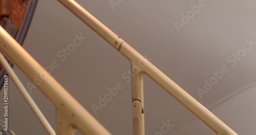 Closeup view of skilled technician inspecting stair fittings in hangar. Polished brass handrail on jet stairs wood door with maintenance technician conducting detailed inspection