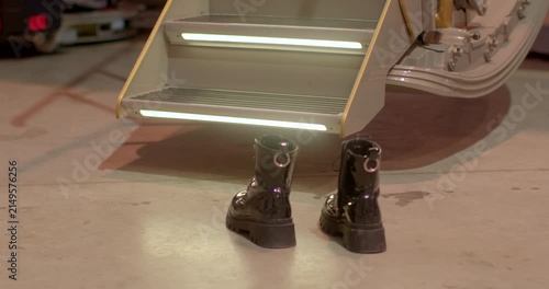 Pair of boots situated next to jet boarding steps inside hangar. Footwear pair placed near aircraft stairs illustrating ground personnel and access scene inside hangar
