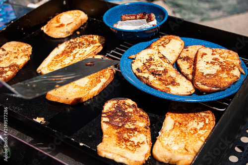 French Toast for Breakfast. A person is cooking french toast for breakfast on a grill outdoors while camping.