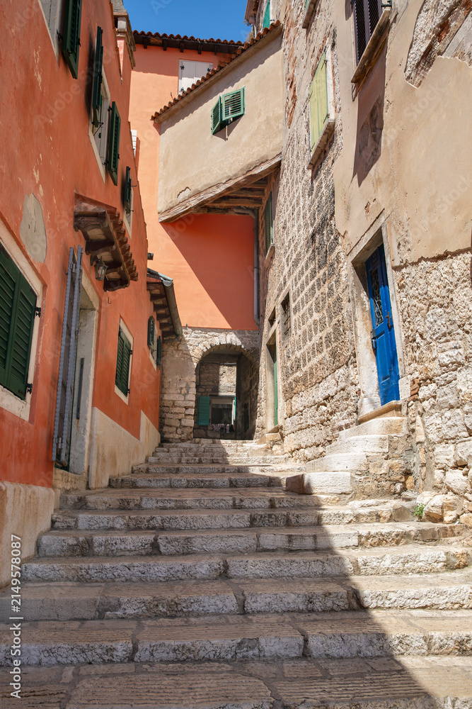 Obraz premium Narrow stone staircase between historic colorful buildings in Rovinj, Croatia.